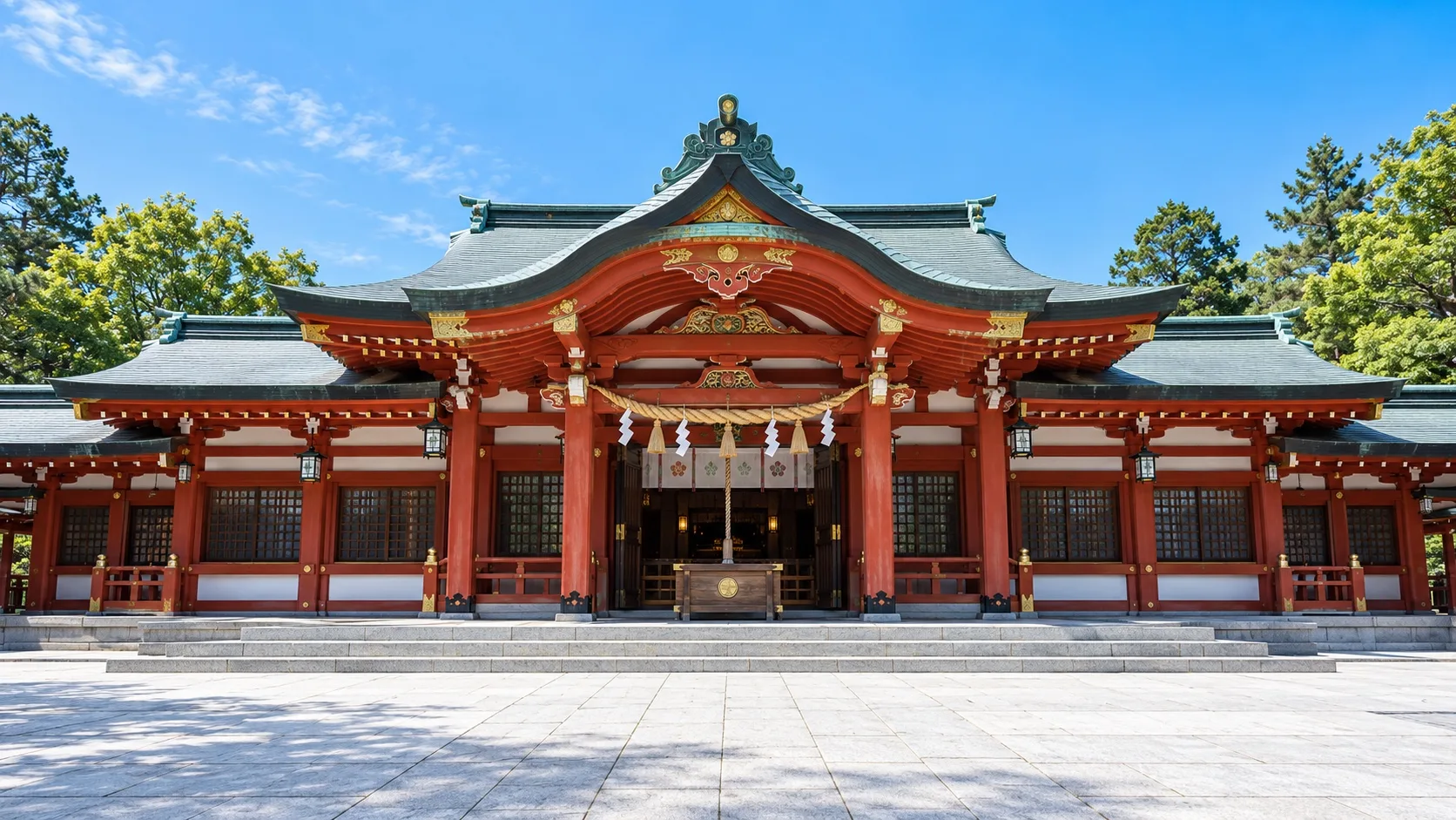 青空の下に建つ朱塗りの赤綴神社拝殿